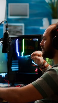 Streamer man talking with multiple players into headphones and winning games competition. Professional gamer streaming online videogames with new graphics on powerful computer from gaming room photo
