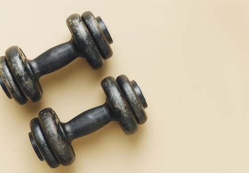 Black Cast Iron Dumbbell With Knurled Handle On Tan Background photo