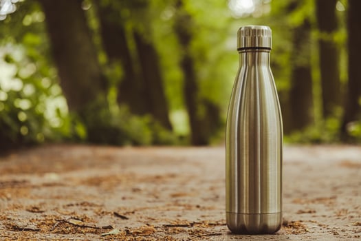 Water bottle. Reusable steel thermo water bottle on green grass. Sustainable lifestyle. Plastic free zero waste free living. Go green Environment protection. Health-conscious. Steel thermo water bottle of silver on background of blurred grass. photo