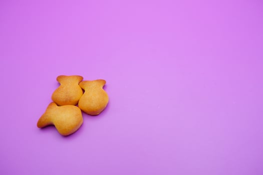 three biscuits shaped like fish isolated on a purple background photo