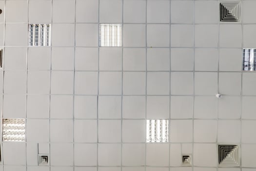 cassette stretched or suspended ceiling with square halogen spots lamps and drywall construction in empty room in house or office. Looking up view photo