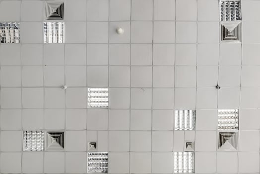 cassette stretched or suspended ceiling with square halogen spots lamps and drywall construction in empty room in house or office. Looking up view photo