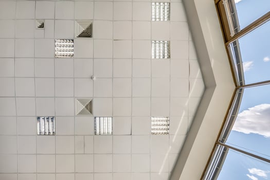 cassette stretched or suspended ceiling with square halogen spots lamps and drywall construction in empty room in house or office. Looking up view photo