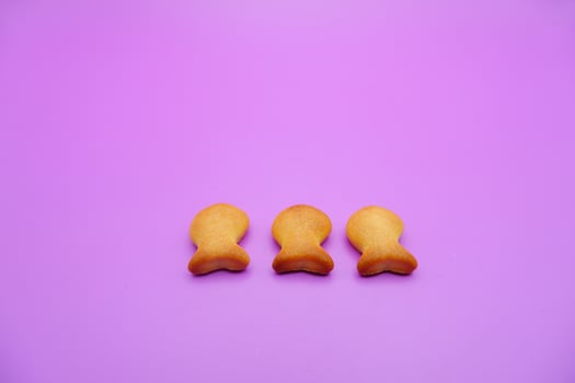three biscuits shaped like fish isolated on a purple background photo