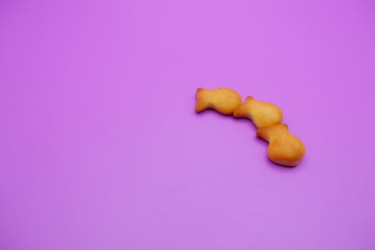 three biscuits shaped like fish isolated on a purple background photo
