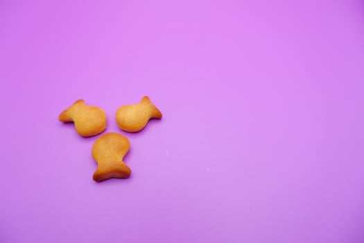 three biscuits shaped like fish isolated on a purple background photo