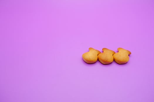 three biscuits shaped like fish isolated on a purple background photo