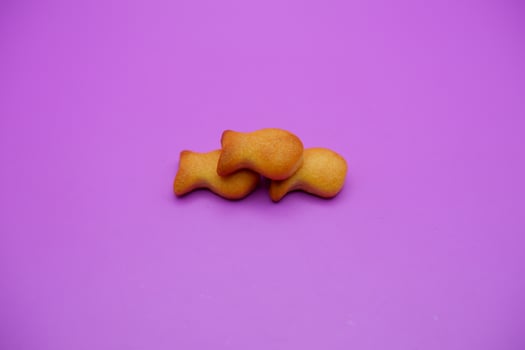 three biscuits shaped like fish isolated on a purple background photo