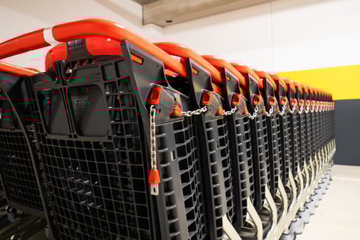 Detailed view of shopping cart handles with a focus on the red locking mechanism and chain photo