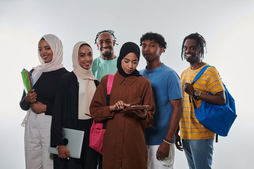 Group of diverse students engages in modern educational practices, utilizing a variety of technological tools such as laptops, tablets, and smartphones against a clean white background, exemplifying photo