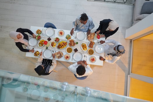 Top view of a Muslim family joyously comes together around a table, eagerly awaiting the communal iftar, engaging in the preparation of a shared meal, and uniting in anticipation of a collective photo