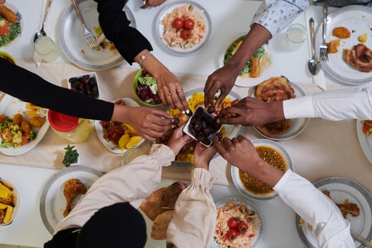 Top view of diverse hands of a Muslim family delicately grasp fresh dates, symbolizing the breaking of the fast during the holy month of Ramadan, capturing a moment of cultural unity, shared tradition photo