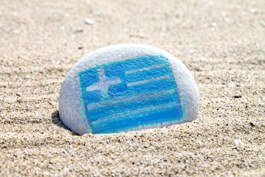 Greece country flag painted on the sea stone on empty sandy beach close up. Vacation concept. photo