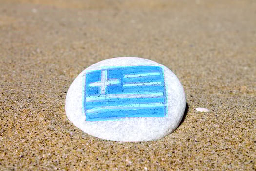 Greece country flag painted on the sea stone on empty sandy beach close up. Vacation concept. photo