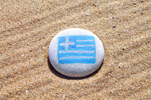 Greece country flag painted on the sea stone on empty sandy beach close up. Vacation concept. photo