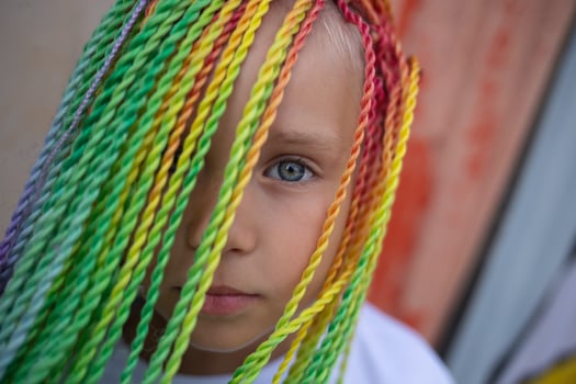 girl with multi-colored african braids on the background of a colorful wall photo