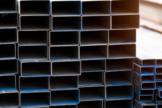 Industrial warehouse stock of rectangular metal pipes for building and construction supplies. Stack of steel pipes. Iron materials for construction and infrastructure projects. Steel tubing storage. photo