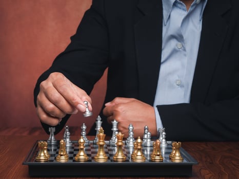 Businessman playing a game of chess on the chessboard while sitting in the office. The decision on the game. Concept of business, strategy, and planning. photo