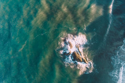 overhead drone aerial view of a rock in the sea at sunrise photo