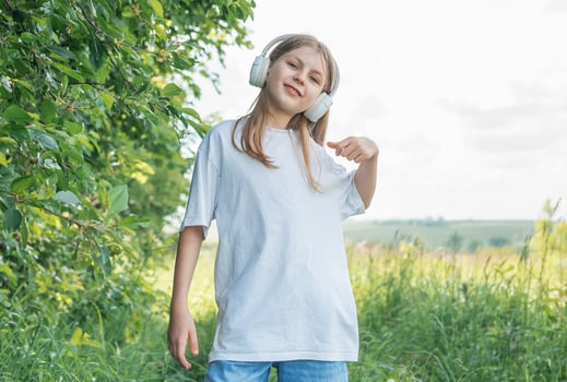 A child with headphones listening to music and dancing in the park. photo