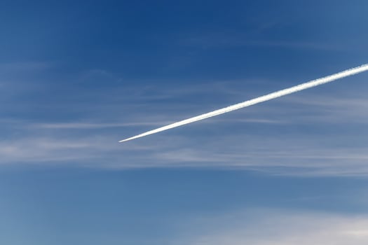 Contrails - one flying transport airplane with condensation trails in a blue sky photo