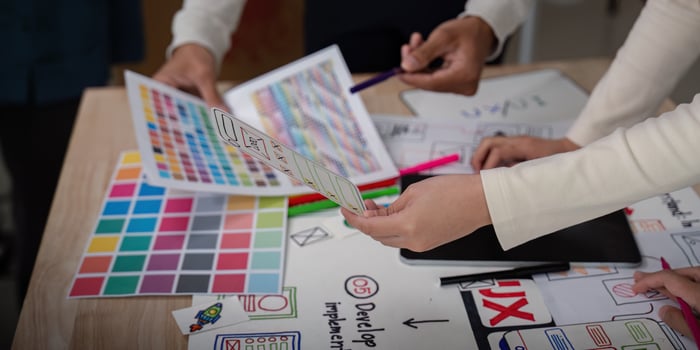 UX Developer and UI Designer Brainstorming Session with Color Palettes and Wireframes on Desk photo