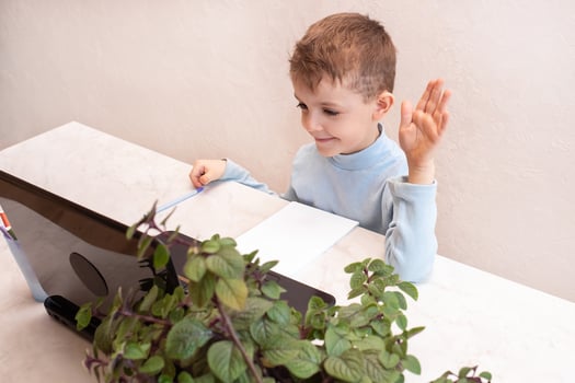 cute boy cheerfully greets the teacher during an online lesson. children's online education photo