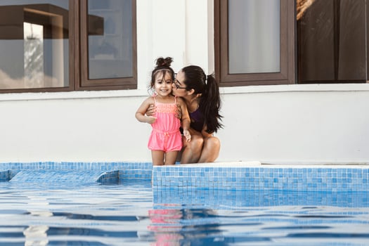 Mother kissing her daughter near the pool. photo