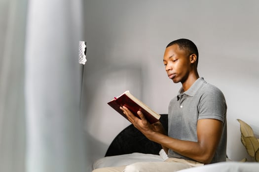 Man in gray shirt reading a book at home. photo