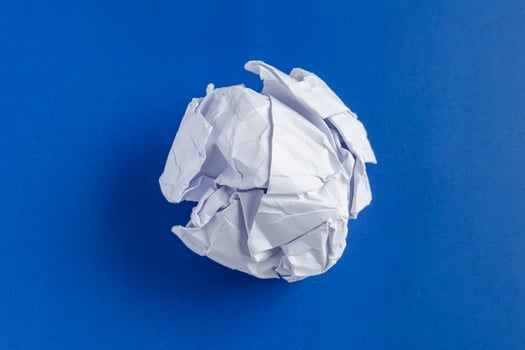 Crumpled junk paper ball on a blue background photo