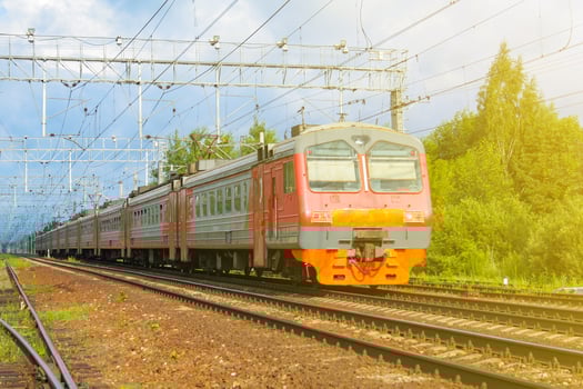 Passenger electric train, illuminated by sunlight moves against the background of green forest photo