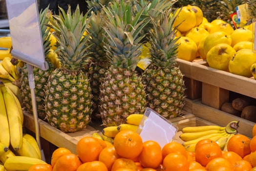 Tropical fruits pineapples, bananas, tangerines on the wooden counter in the supermarket photo