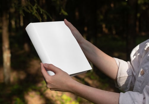 . Blank book hard cover, hardback mock up in hand in nature, sunny summer day. photo