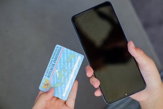 human hand holding Indonesian identity card or e-KTP and smartphone. photo