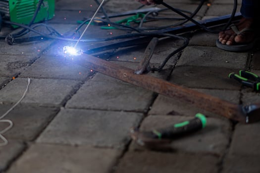 Person welding metal rod on tiled floor photo