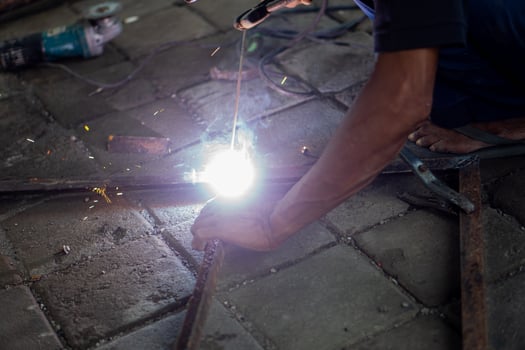 Person welding metal pieces on tiled floor photo