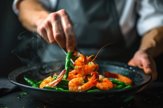 Chef cooking shrimps in the kitchen. Professional cook preparing prawn salad. Healthy seafood with vegetables photo