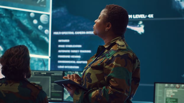 Woman high tech specialist studying satellite CCTV visualization on a big screen, preparing troops with insight for a new national safety mission. Female first lieutenant in command post. Camera A. photo