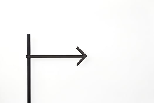 Black arrow sign on white wall photo