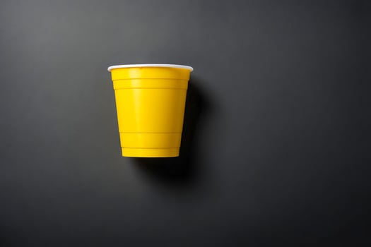 Yellow Plastic Cup on Black Background photo