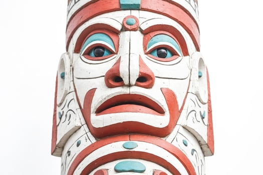 Closeup of a totem pole with a carved human face photo