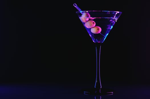 Martini glass and olives on a black background with neon lights photo