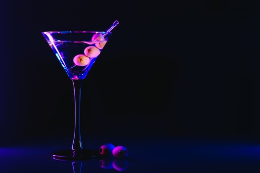 Martini glass and olives on a black background with neon lights photo