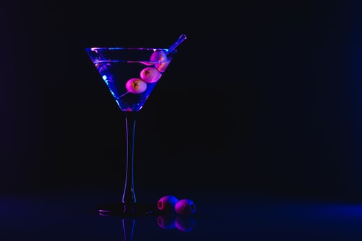 Glass of classic dry martini cocktail with olives on dark stone table against black background. With free space for your text photo