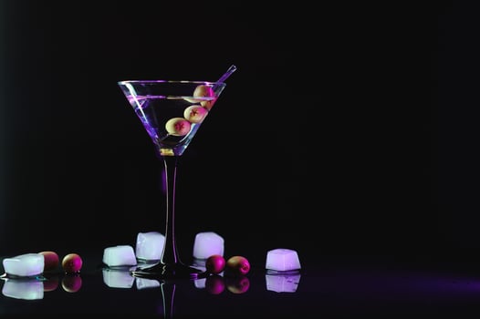 Glass of classic dry martini cocktail with olives on dark table against black background. With free space for your text photo