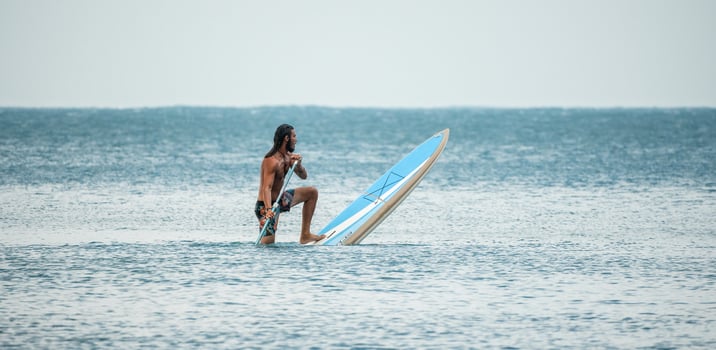 Sea man sup. Asian athlete man swimming in sea and paddleboarding at summer sunset. Healthy strong male enjoy outdoor active lifestyle and water sports on holiday vacation. photo