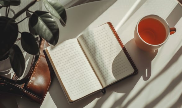 Closed notebook on a white table with a cup of coffee and a handbag photo