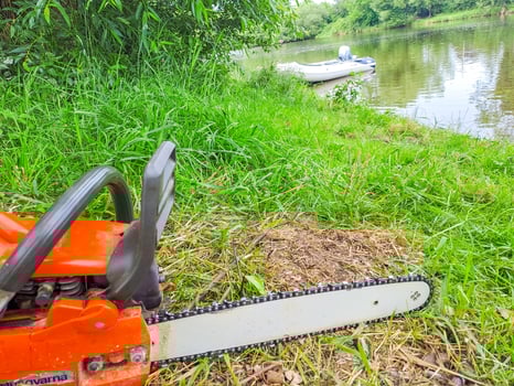 A view of a gasoline Chainsaw,Chain saw, on the grass by the river. Czech photo