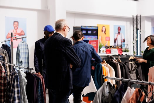 Group of diverse people shoppers standing in clothing store choosing clothes at discounted prices. Customers going crazy at Black Friday sales, hunting for bargains during seasonal fashion discounts photo