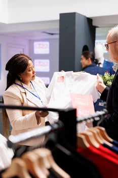 Friendly African American woman clothing store worker assisting customer with purchase decision during Black Friday sales. Shop assistant helping senior man to choose clothes at discounted prices photo